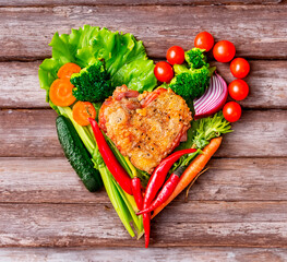 still life of fried meat with vegetables on a plate in the shape of a heart.