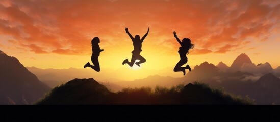 Silhouette three people jumping on mountain sunset sky background.Silhouette jumping team.