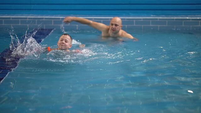 family in the pool. the boy makes movements. slow motion video. the boy is studying. High-quality shooting in 4K format.