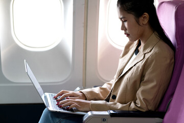 young businesswoman uses laptop while flying airplane for work