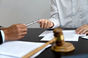 lawyer handing a pen to a client or business associate to sign a contract - obrazy, fototapety, plakaty