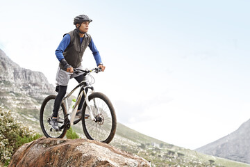 Man, mountain bike and off road cycling with mockup space on nature adventure or fitness in outdoor extreme sport. Male person or cyclist on bicycle for cardio on cliff hill in exercise with blue sky - obrazy, fototapety, plakaty