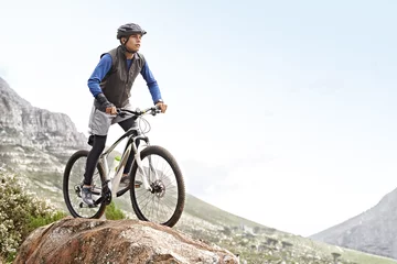 Fotobehang Man, mountain bike and off road cycling with mockup space on nature adventure or fitness in outdoor extreme sport. Male person or cyclist on bicycle for cardio on cliff hill in exercise with blue sky © Alexandra/peopleimages.com