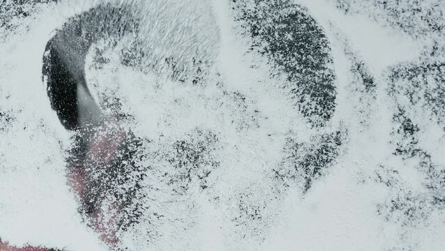 Close-up of fluffy brush on a snow-covered glass surface erases romantic heart shape love symbol. End of love or end of relationship