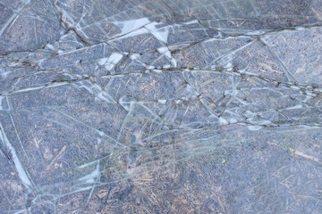 gray texture of a broken piece of glass with cracks in the street