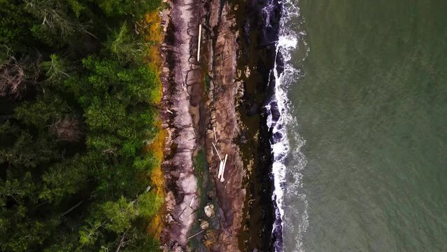 Aerial Bird's eye view of a rocky ocean coastline with rainforest near Vancouver Island, Canada