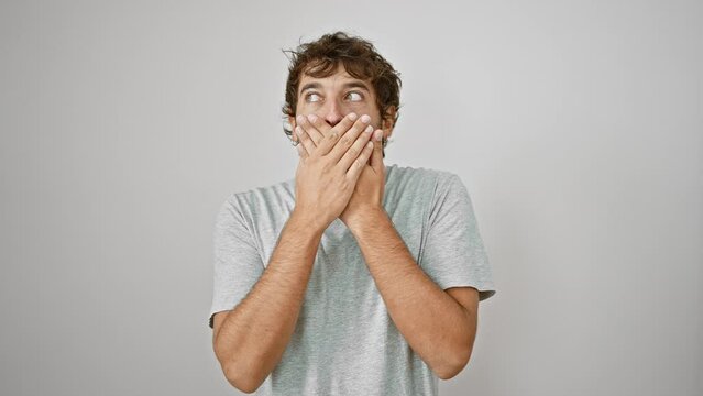 Shell-shocked young man covers mouth with hands in dismay over mistake. secret worried expression on white isolated background.