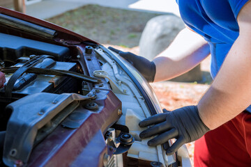 During car repair, mechanic assembles headlight on an automobile