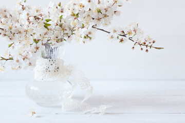 Blooming cherry plum branches in a vase on a white wooden table, copy space, blur, selective focus - 707944101