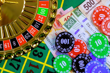 Casino roulette with Mexican banknotes peso, poker chips on green gaming table
