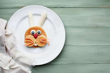 Fun, colorful creative pancake bunny rabbit for children with banana, blueberries, carrots and raspberries to encourage kids to eat healthy foods.