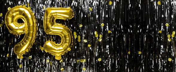 Gold foil balloon number number 95 on a background of black tinsel decoration. Birthday greeting...