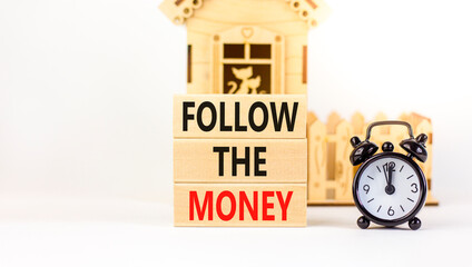 Follow the money symbol. Concept words Follow the money on beautiful wooden blocks. Beautiful white table white background. Black alarm clock. Business and follow the money concept. Copy space.