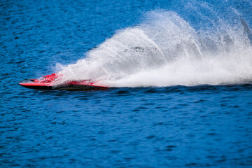 RC racing boat straightaway skips across the water leaving behind huge spray and ripples.