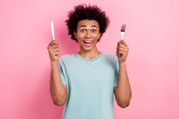 Photo portrait of handsome young male hold fork knife lick tongue hungry dressed stylish blue garment isolated on pink color background - obrazy, fototapety, plakaty