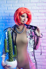 Stylish young girl in a wig and bright clothes in neon light at a fashionable party