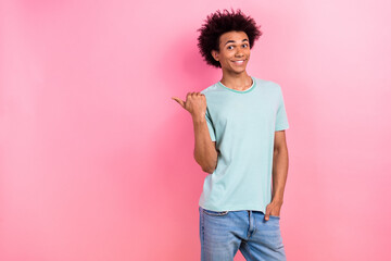 Photo of cheerful funky guy wear blue t-shirt showing thumb empty space isolated pink color...