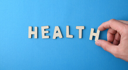 Hand composing health with letter cutouts on blue top view