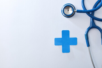 Health concept with stethoscope and blue cross on white background