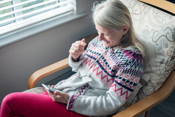 A middle aged woman,using her smartphone,at home,checking up on friends,Worcestershire,England,UK.