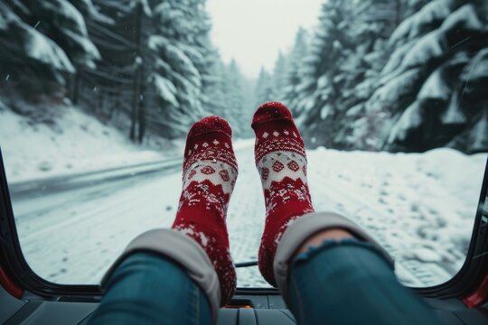Feet of a person sticking out of a car window in the snowy weather. Can be used to depict a winter road trip or the joy of playing in the snow