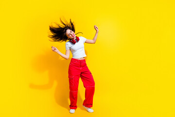 Full length photo of dreamy cheerful woman dressed t-shirt headphones flying hair discotheque empty space isolated yellow color background