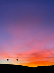 Two Gondola Cabins against Backdrop of Sunrise