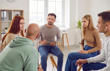 People communicating in group therapy. Adult men and women having psychotherapy session with...