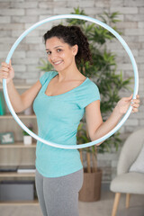 young woman doing exercises in gym with huyla hoop
