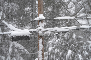 Utility pole and wires covered with snow in blizzard