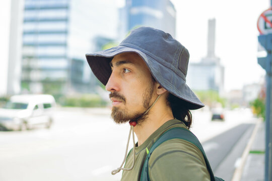 portrait of a young Latin man in profile wearing a bucket hat in the city to protect himself from the sun