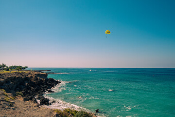 Meereslandschaft mit einem gelben Gleitschirm in einem blauen wolkenlosen Himmel. Zyperns...