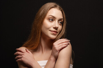 Beauty portrait of a pretty blonde girl looking tenderly against a black background