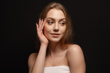 Beauty portrait of a pretty blonde girl looking tenderly against a black background