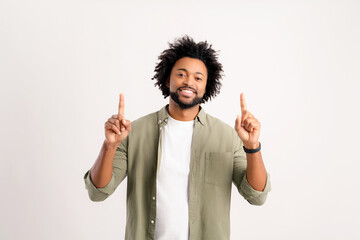 Happy excited young man looking at camera pointing up with both hands, gesturing at copy space...