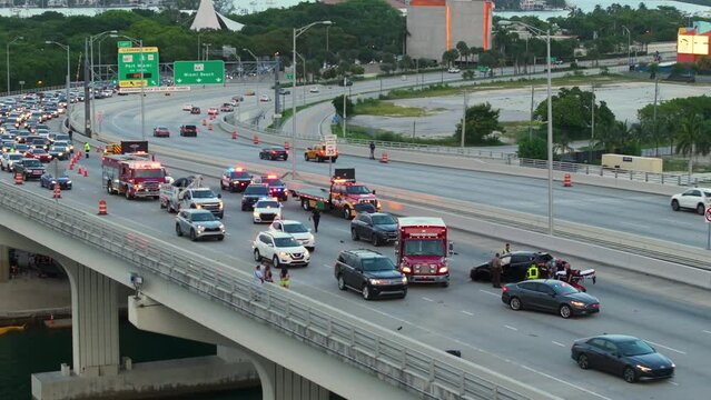 Car accident on highway bridge in Miami, Florida. Emergency services personnel helping victims of vehicle crash on city street bridge in USA