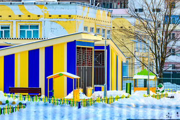 New colorful modern kindergarten building with playgrounds in snowy winter. The concept of placing a child in kindergarten on a first-come, first-served basis.