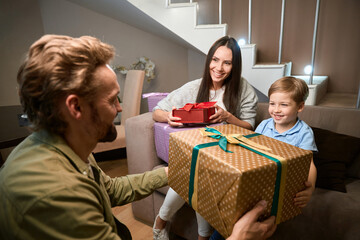 Happy father congratulating his little son with New Year holiday giving present
