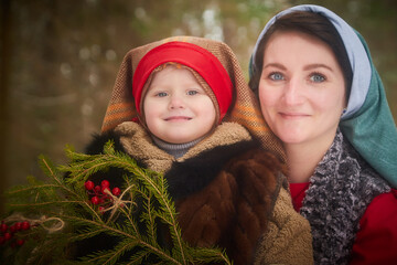 Family with mother and little daughter in stylized medieval peasant clothing in winter forest. The...