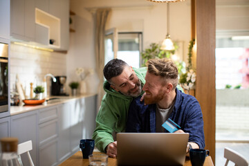 Male gay couple online shopping with laptop from home