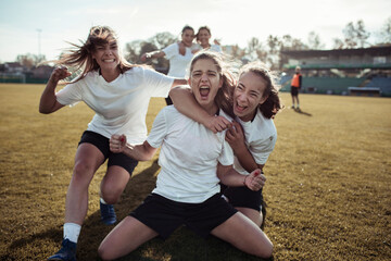 Young female football team celebrating a goal on the soccer field
