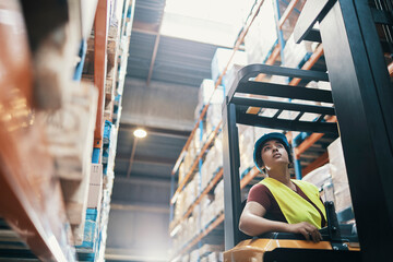 Young female warehouse worker operating forklift