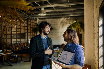 Group of colleagues laughing and discussing project on laptop in a bright modern office