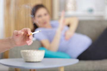 young pregnant women raise her hand against smoke