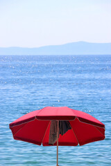 Colorful parasol on the beaach, by the sea. Sunny summer day. Selective focus.