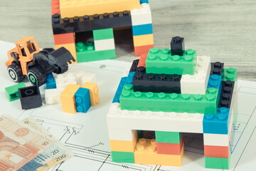 Small houses made of toy blocks, housing plan with electric installation and euro banknotes. Building or renting home