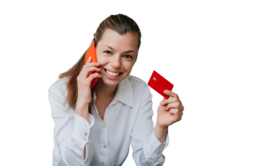 Happy young woman in white shirt and black pants sitting on chair talking by phone showing credit card looking at camera against transparent background. Business people and wealthy life