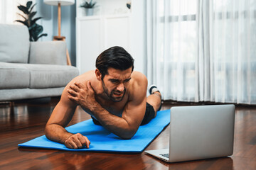 Athletic and sporty man suffer from exercise injury during online body workout exercise session at...