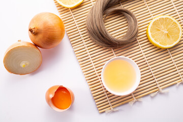 Hairloss concept. Onions, lemon, egg and hair isolated on a wooden background