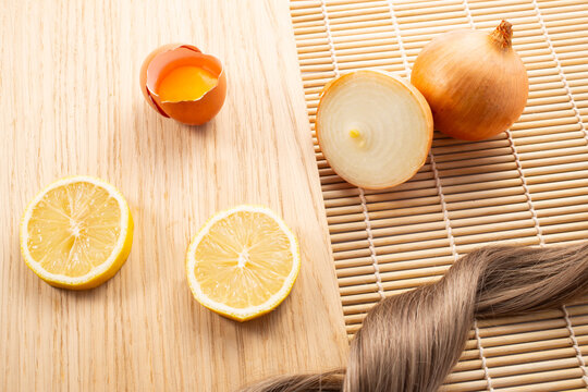 Hairloss concept. Onions, lemon, egg and hair isolated on a wooden background